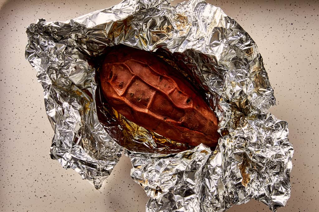 Roasted sweet potato opened after slow roasting, showing a soft, syrupy interior.