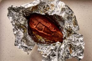 Roasted sweet potato opened after slow roasting, showing a soft, syrupy interior.