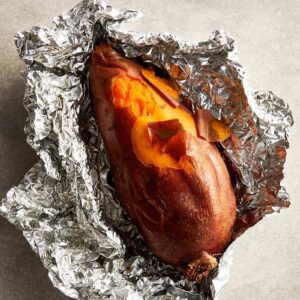 Roasted sweet potato opened after slow roasting, showing a soft, syrupy interior.