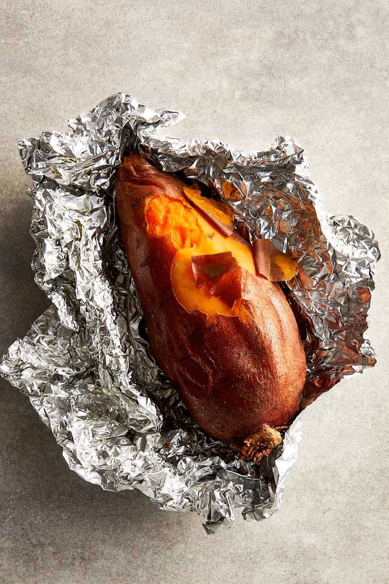 Roasted sweet potato opened after slow roasting, showing a soft, syrupy interior.