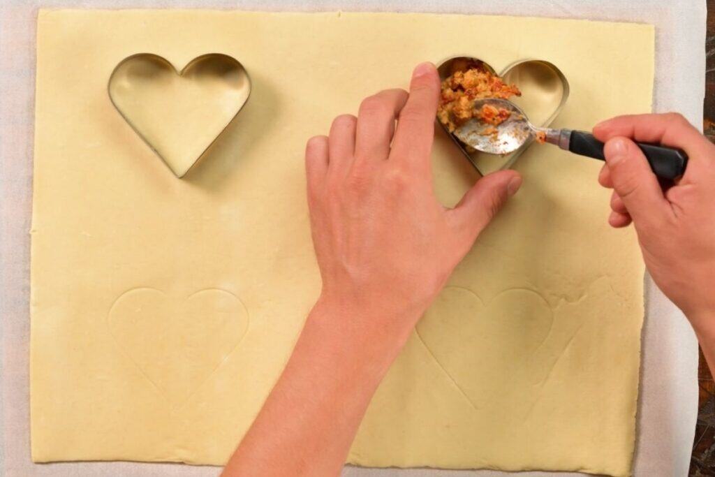 top down view of a cookie stencil shaped heart being filled with chicken mince