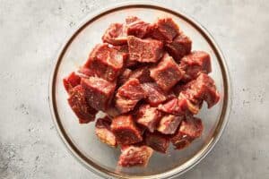 Top overview of pieces of raw steak in a bowl