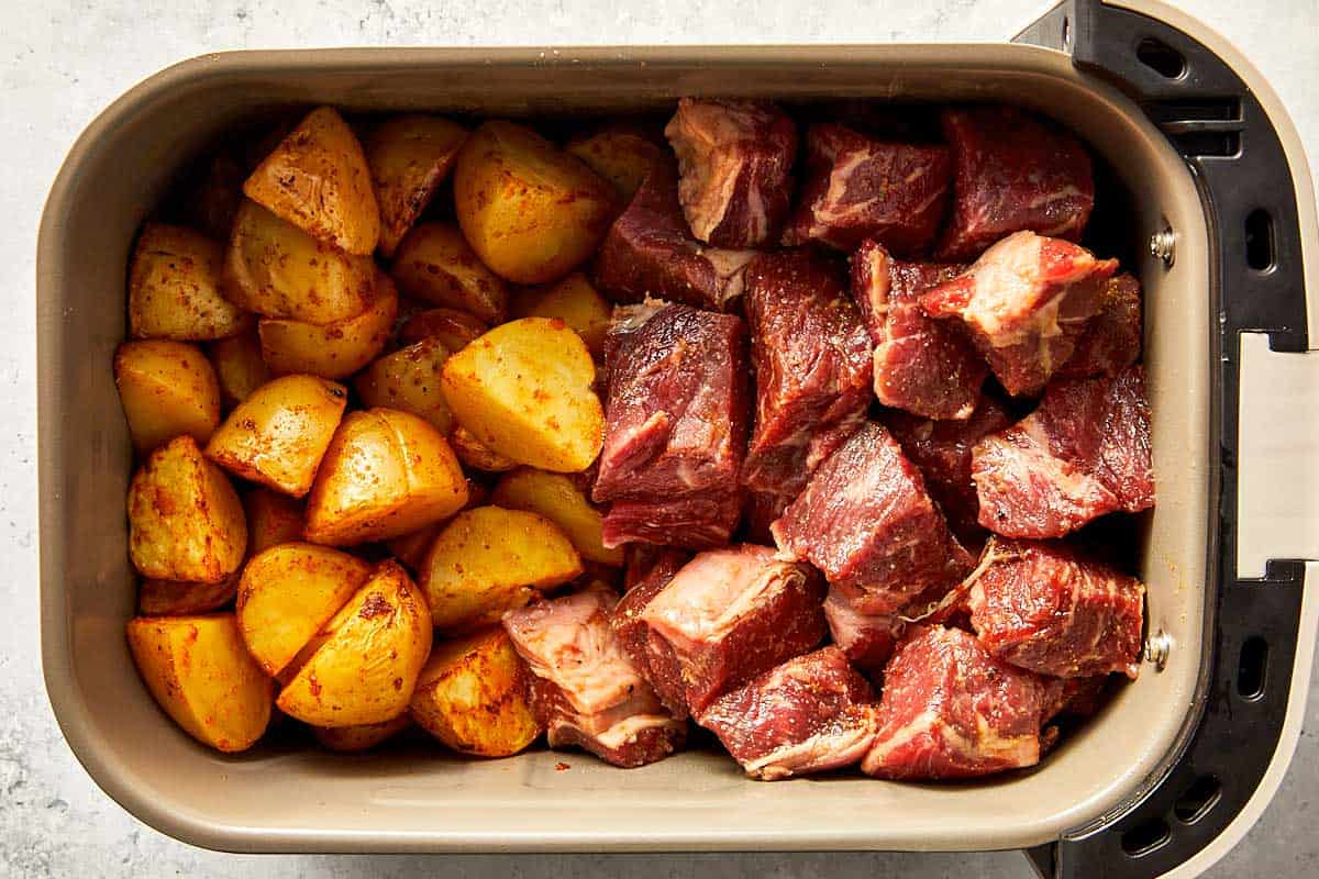 Top overview of potatoes and raw steak in the air-fryer