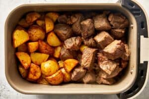 Top overview of potatoes and cooked steak in the air-fryer