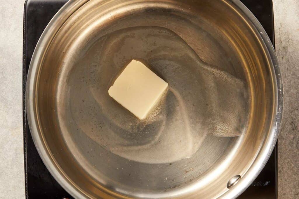 Butter melting in a large pan over medium heat, starting the base for creamy corn recipe