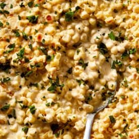 Creamy corn casserole with a golden broiled top and chopped parsley, served warm