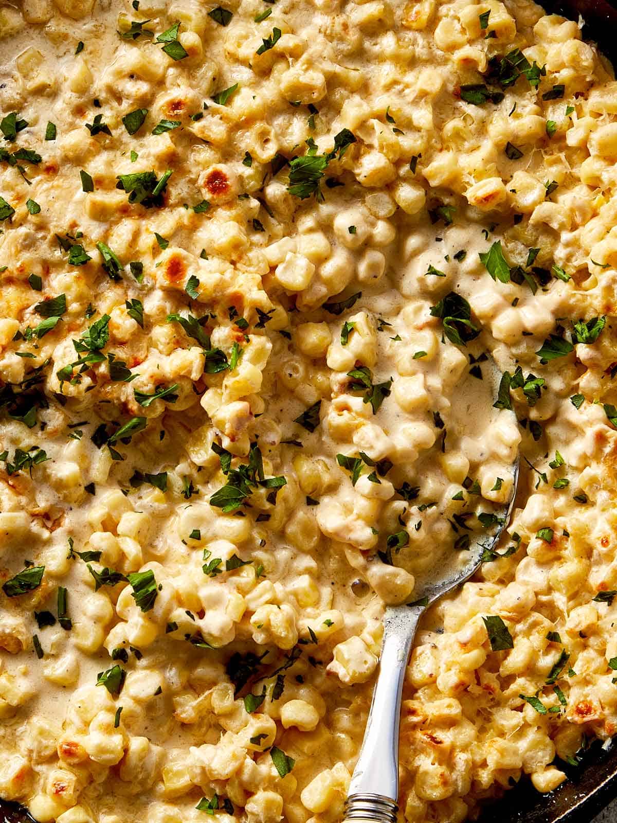 Creamy corn casserole with a golden broiled top and chopped parsley, served warm