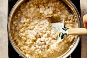 Corn simmering in a creamy garlic sauce with cream cheese and stock, stirred until thick and coated
