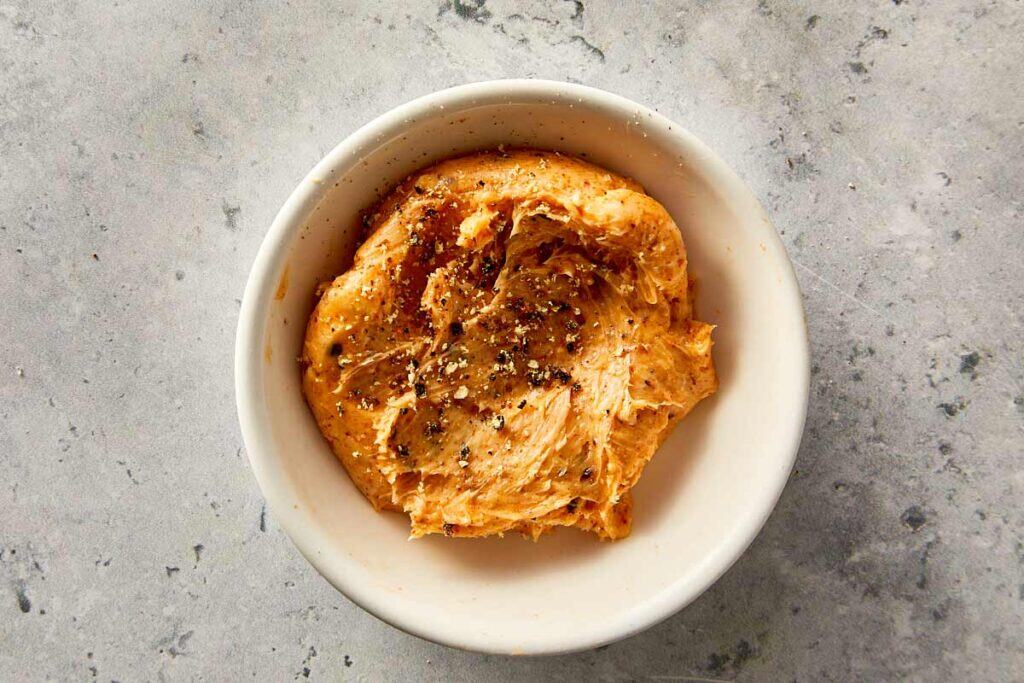 Garlic butter with spices in a small bowl, ready to spread over baked sweet potatoes