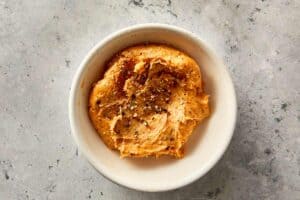 Garlic butter with spices in a small bowl, ready to spread over baked sweet potatoes