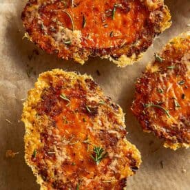 Crispy baked sweet potatoes with melted Parmesan and herbs on parchment paper