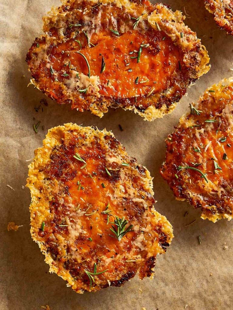 Crispy baked sweet potatoes with melted Parmesan and herbs on parchment paper