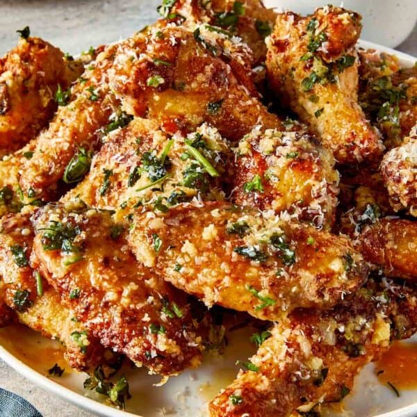 garlic parmesan chicken wings on plate with crispy skin, melted butter, parmesan cheese and fresh parsley