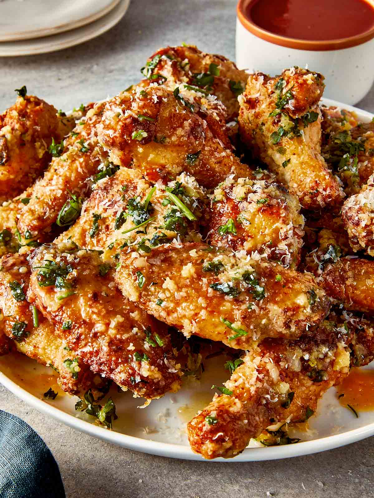 garlic parmesan chicken wings on plate with crispy skin, melted butter, parmesan cheese and fresh parsley