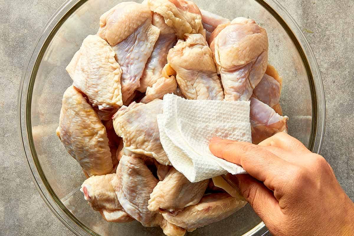patting raw chicken wings dry with paper towel before seasoning