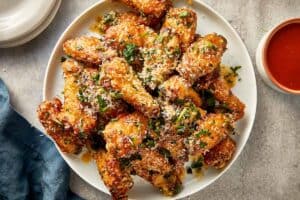 garlic parmesan chicken wings fully coated with cheese and parsley ready to serve