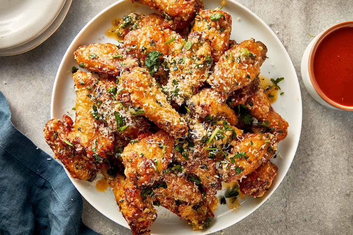 garlic parmesan chicken wings fully coated with cheese and parsley ready to serve