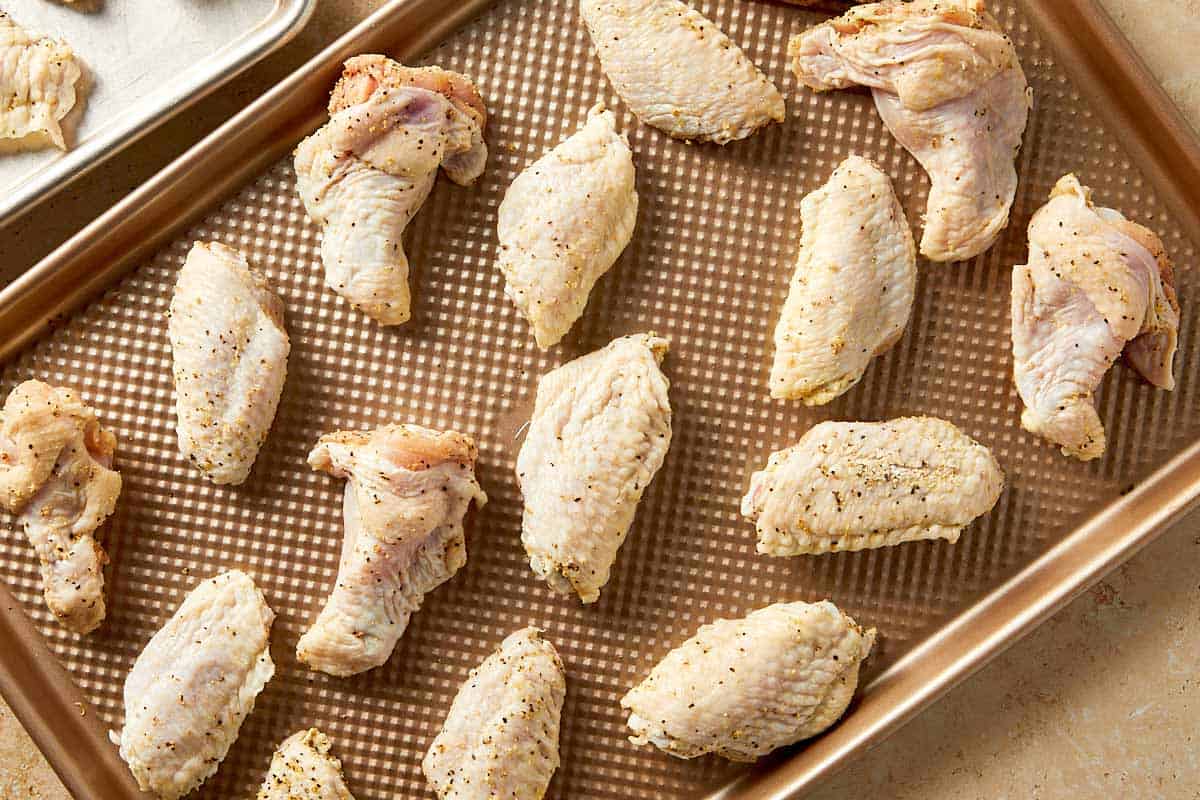 Seasoned lemon pepper chicken wings arranged in a single layer on a baking tray, spaced apart for even cooking and crisping
