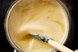 Melted butter being whisked in a saucepan over heat, starting the lemon pepper sauce base