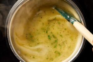 Lemon pepper butter sauce simmering in a saucepan, fully combined with herbs and seasoning