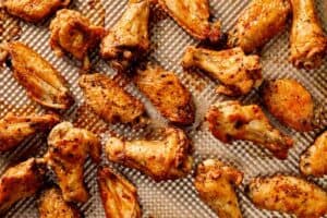 Crispy baked lemon pepper chicken wings on a tray, golden and evenly browned with a lightly seasoned coating