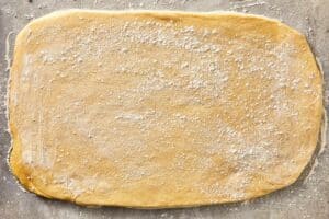 Dough rolled into a large rectangle on a floured surface
