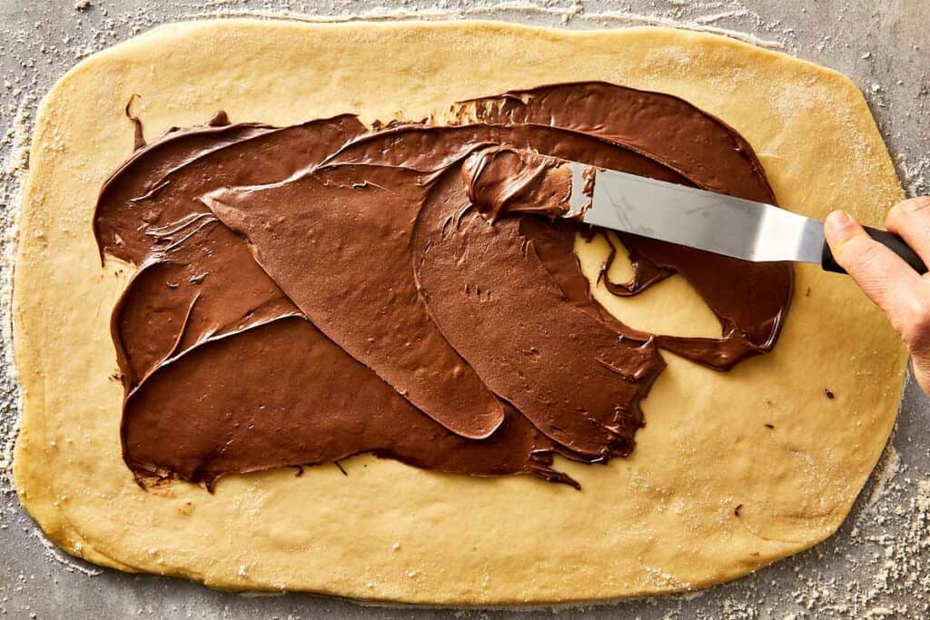 Nutella being spread over rolled dough