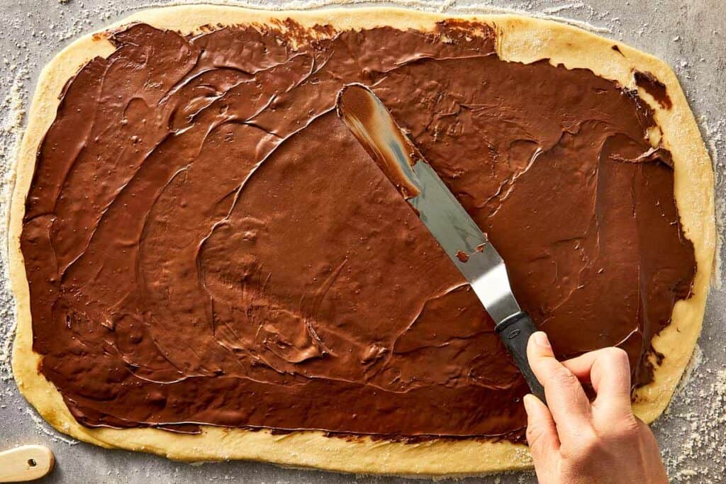 Nutella evenly spread across the dough with a spatula