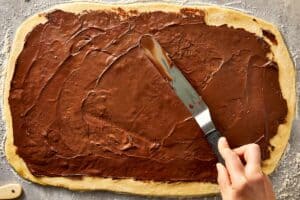 Nutella evenly spread across the dough with a spatula
