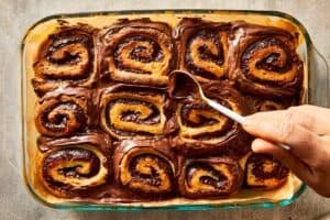 Melted Nutella being spread over warm baked rolls