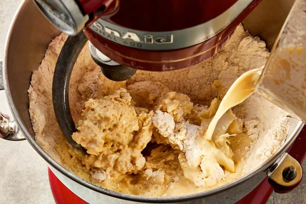Dough ingredients being mixed in a stand mixer with dough hook