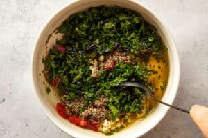 Top overview of chimichurri being mix in a white surface