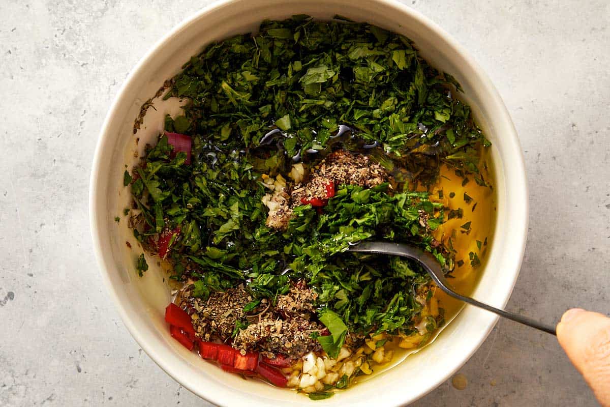 Top overview of chimichurri being mix in a white surface
