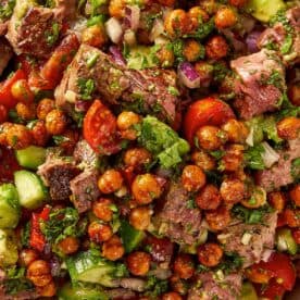 Alt text: steak and chickpea salad with chimichurri tomatoes cucumber avocado and red onion