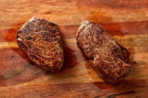 resting cooked steak on a cutting board before slicing for salad