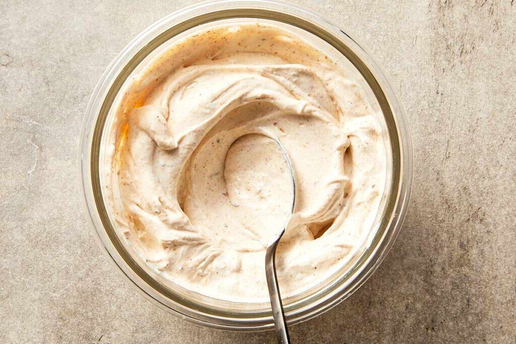 Top view of sour cream being mixed with a spoon.