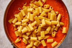 Dry rigatoni pasta added directly into the blended tomato soup, ready to cook and absorb the sauce.