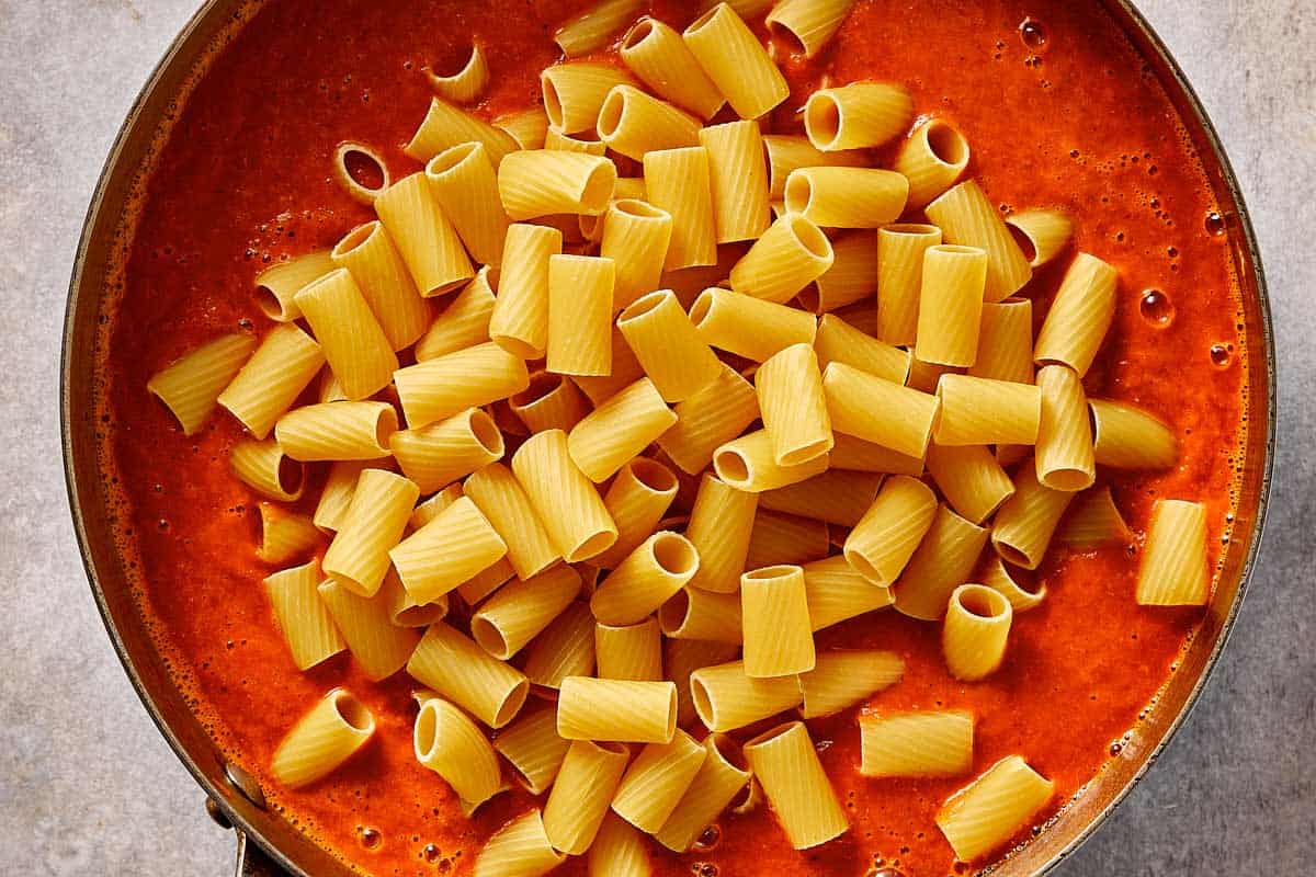 Dry rigatoni pasta added directly into the blended tomato soup, ready to cook and absorb the sauce.