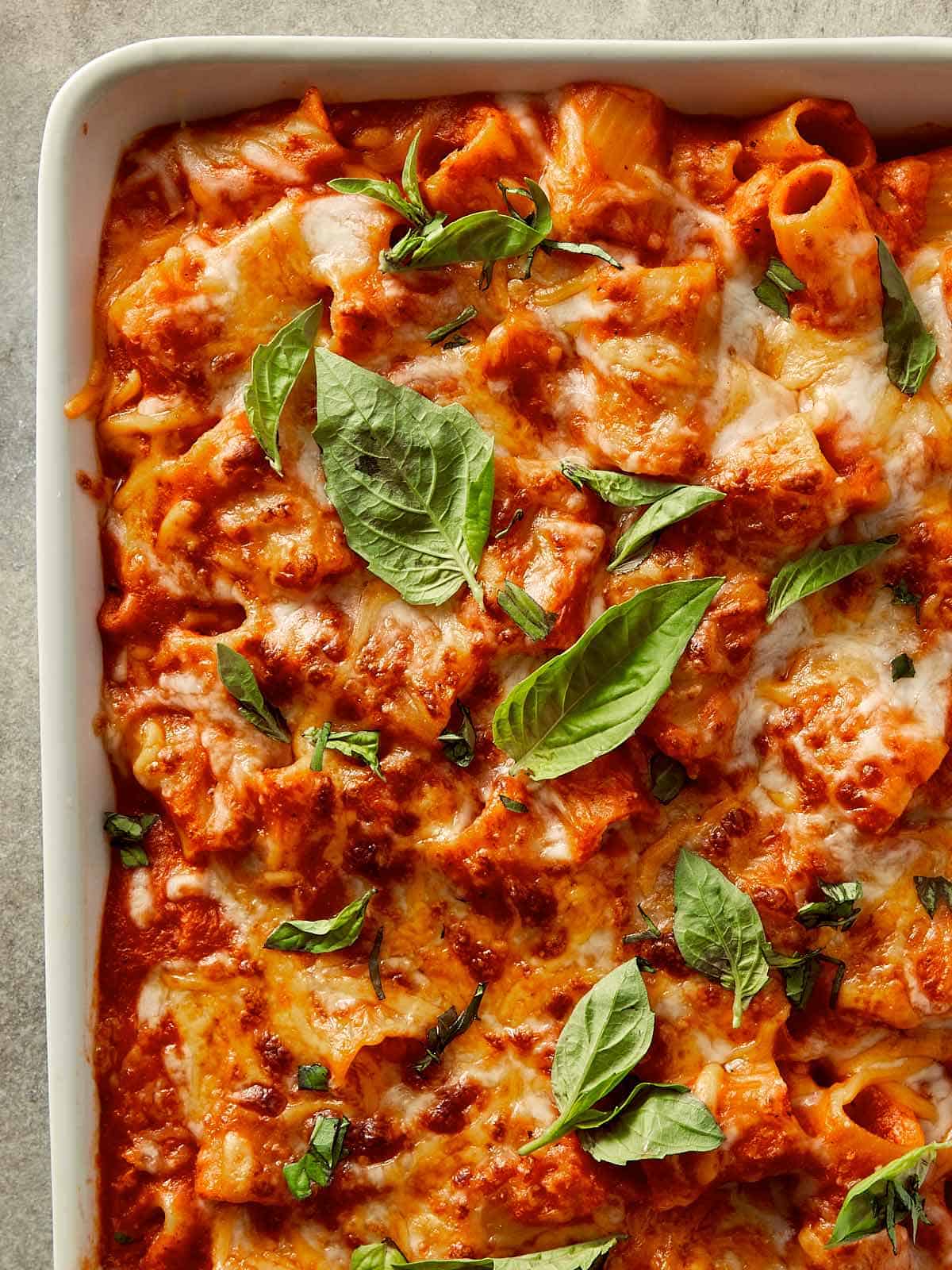 Tomato soup mac and cheese baked until golden and bubbly, made with rigatoni pasta in a rich roasted tomato sauce, topped with melted cheddar and mozzarella, and finished with fresh basil leaves.