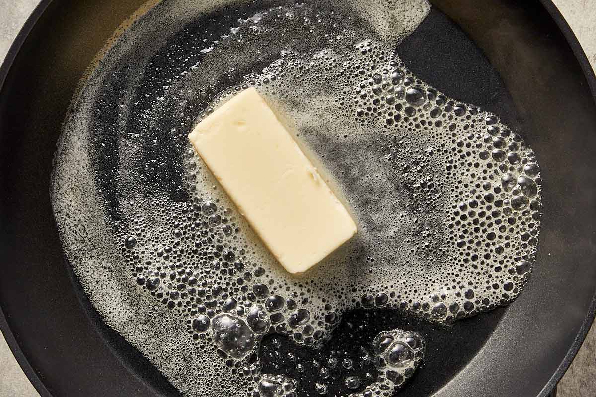 Butter melting in a pan, beginning to foam as it cooks before browning for Alfredo sauce.