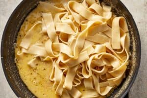 Cooked fettuccine added to the brown butter Alfredo sauce before tossing.