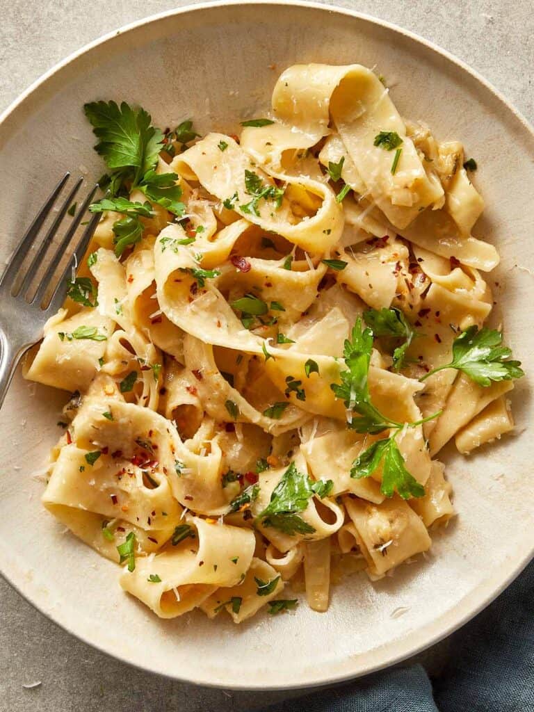 Brown butter fettuccine Alfredo served in a bowl with a creamy parmesan sauce, fresh parsley and chilli flakes.