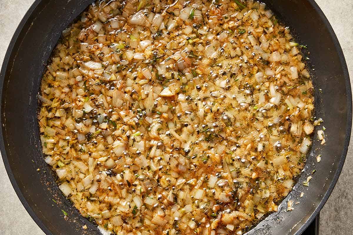 Shallots and garlic cooking in browned butter with herbs until soft and lightly golden.