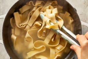 Fettuccine pasta cooking in boiling water until al dente.