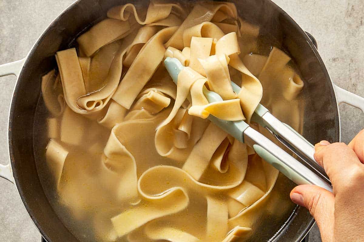 Fettuccine pasta cooking in boiling water until al dente.