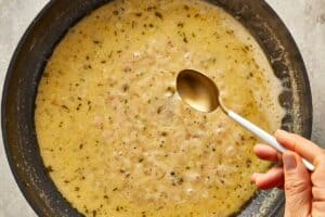Creamy brown butter Alfredo sauce simmering with shallots and herbs until smooth.