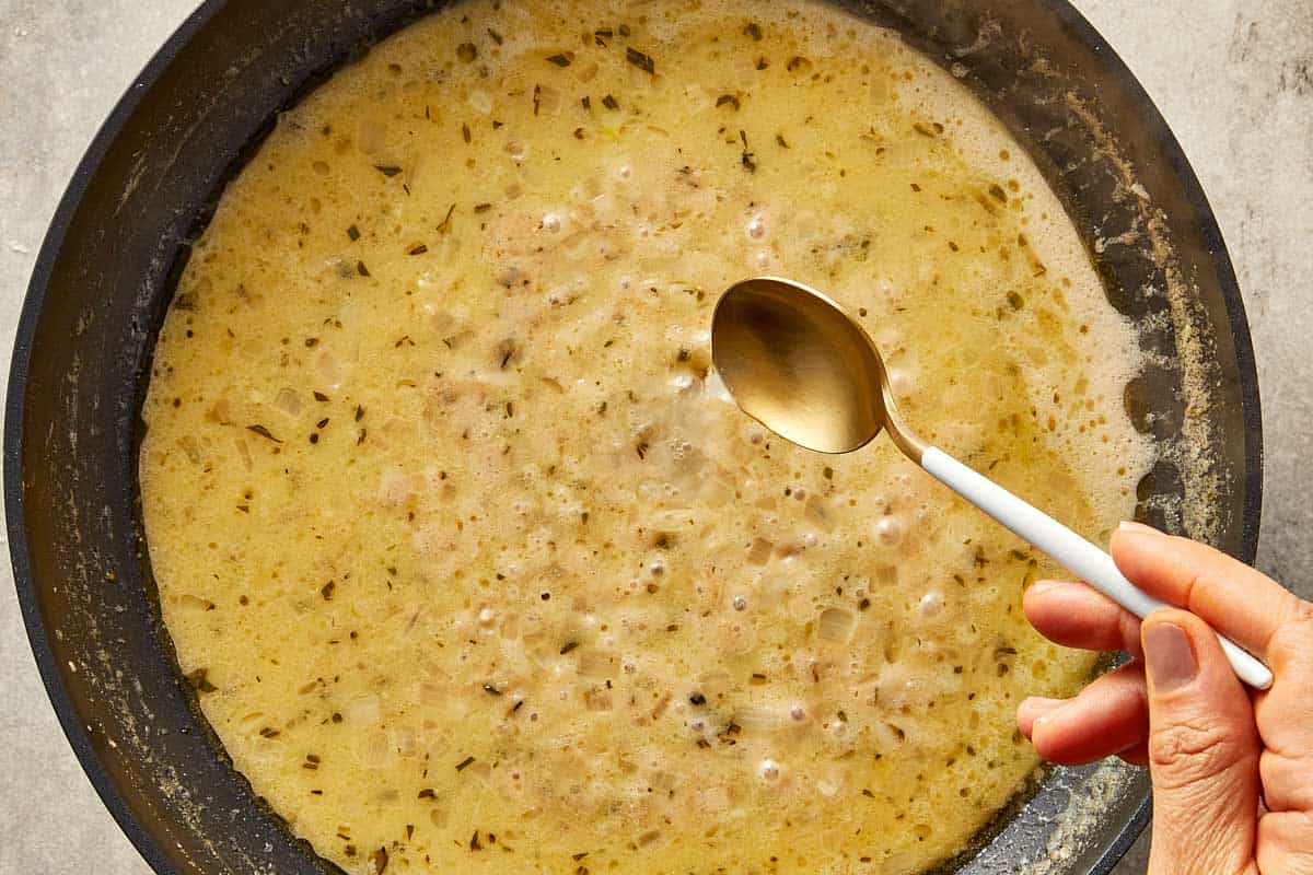 Creamy brown butter Alfredo sauce simmering with shallots and herbs until smooth.