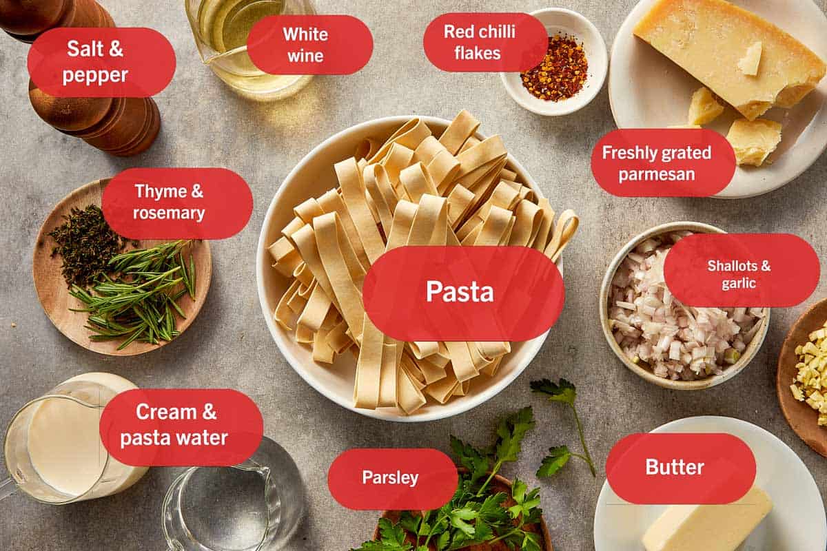 Brown butter Alfredo ingredients including fettuccine pasta, butter, garlic, shallots, parmesan, white wine, cream, fresh herbs, chilli flakes, salt and pepper arranged on a table.