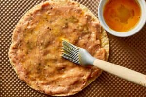 Raw chicken spread evenly over tortilla with egg wash brushed on top