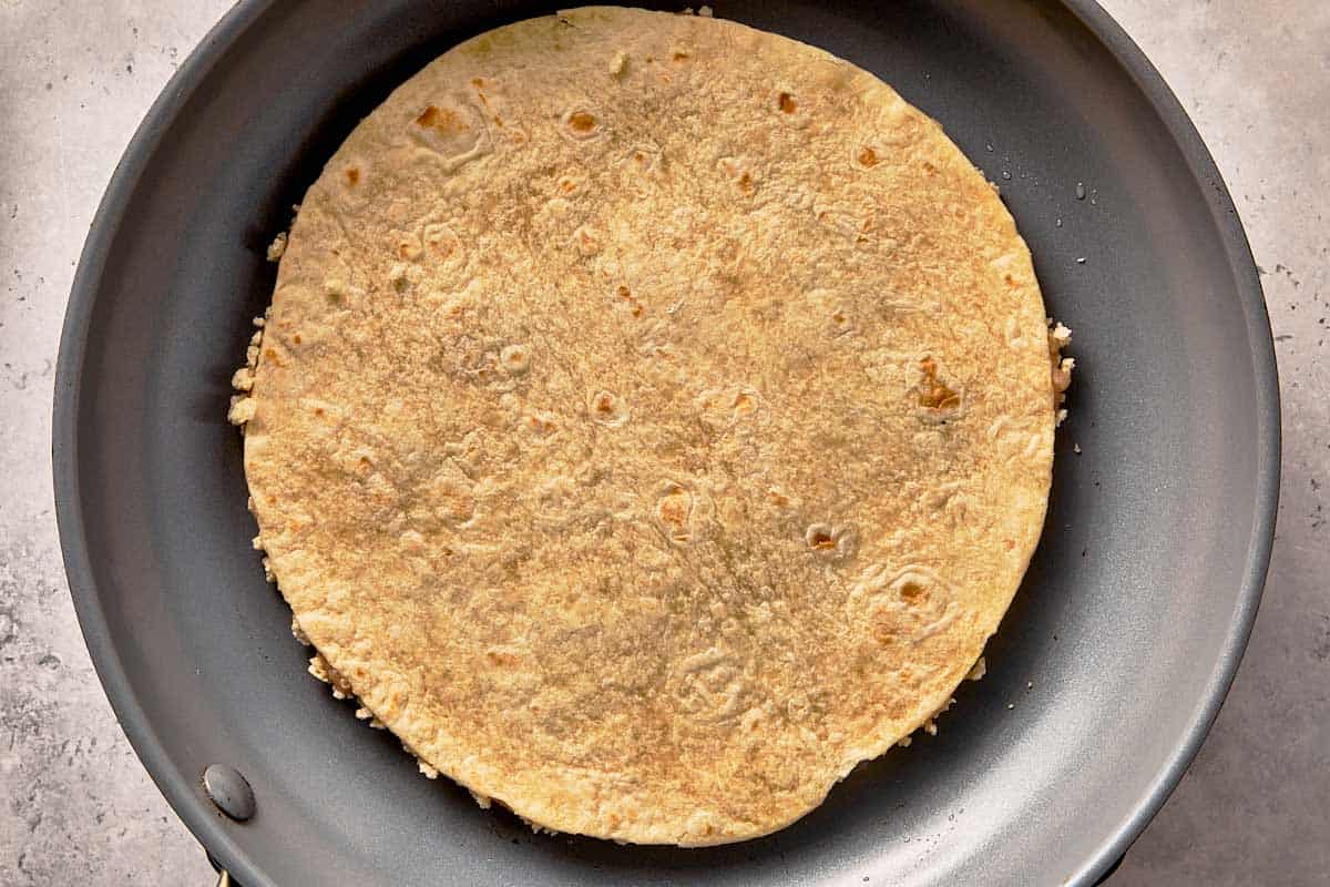 Chicken smashed taco cooking chicken-side down in a pan